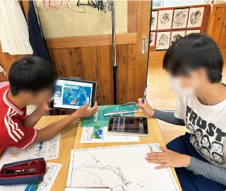 タブレットでハザードマップを見ながら、地図を書き写している生徒たち