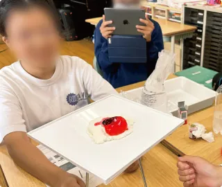 白い板にのせた模型を使って実験している生徒