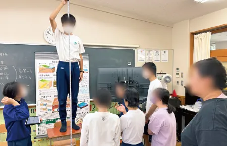 教室の前で長い棒を立て、高さを確かめている生徒たち