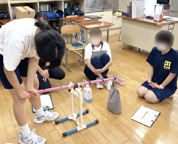 床に置いた器具を使って実験に取り組む生徒たち